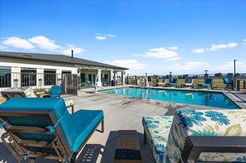 a swimming pool with lounge chairs and a building in the background